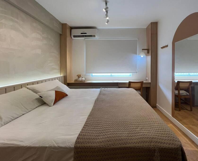 een slaapkamer met een groot bed en een groot raam bij Apartamento na Quadra do Mar com pisicina in Balneário Camboriú
