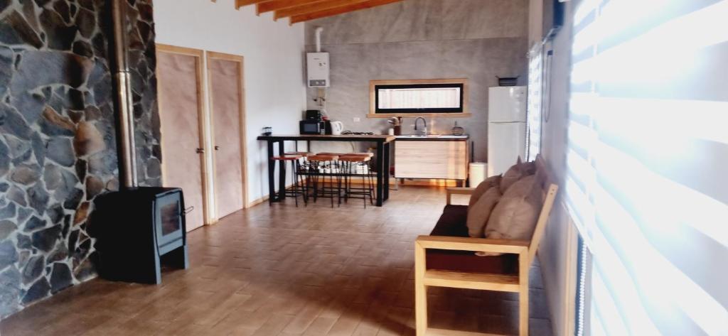 ein Wohnzimmer mit einem Steinkamin und einer Küche in der Unterkunft Gran Cabaña con tinaja privada, Curacautín C in Curacautín