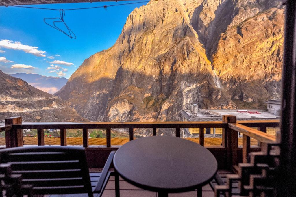 einen Tisch und Stühle auf einem Balkon mit Bergblick in der Unterkunft Tibet Guesthouse 虎跳峡卓玛客栈 in Shangri-La