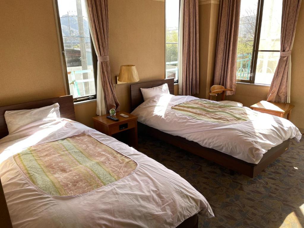 2 camas en una habitación de hotel con 2 ventanas en Hotel Nissin Kaikan - Vacation STAY 02342v, en Shiso