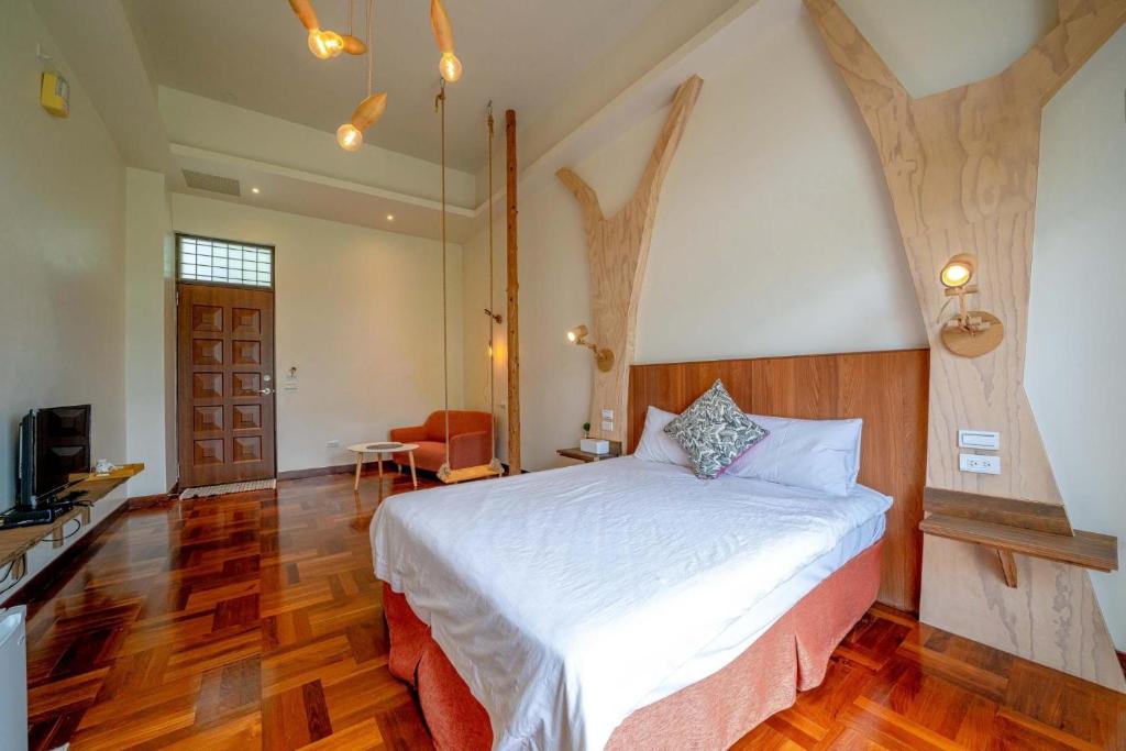 a bedroom with a white bed and a wooden floor at Yun Tien Feng Chuan B&amp;B in Dongshan