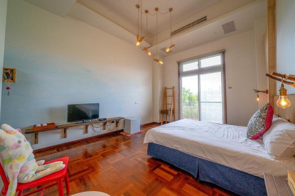 a bedroom with a bed and a tv and a chair at Yun Tien Feng Chuan B&amp;B in Dongshan