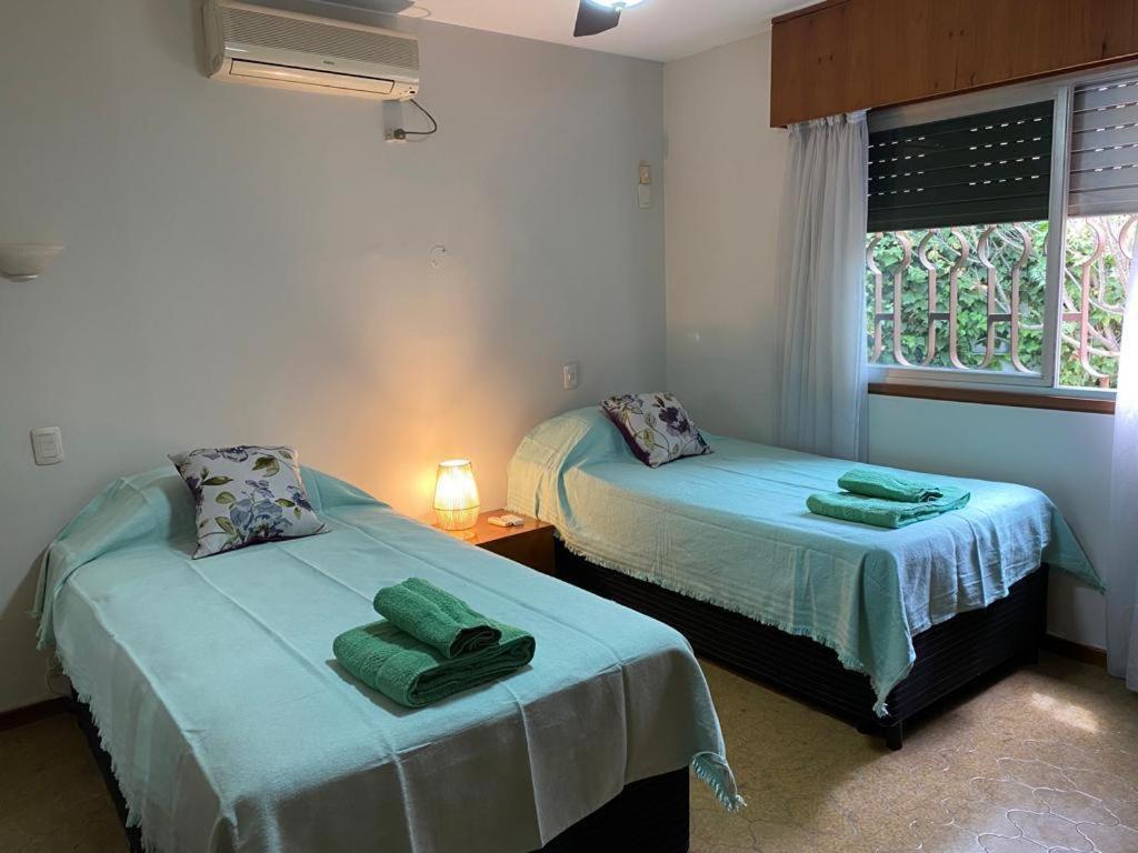 2 camas en una habitación con ventana y 2 toallas en Casa Grande con estacionamiento en San Juan