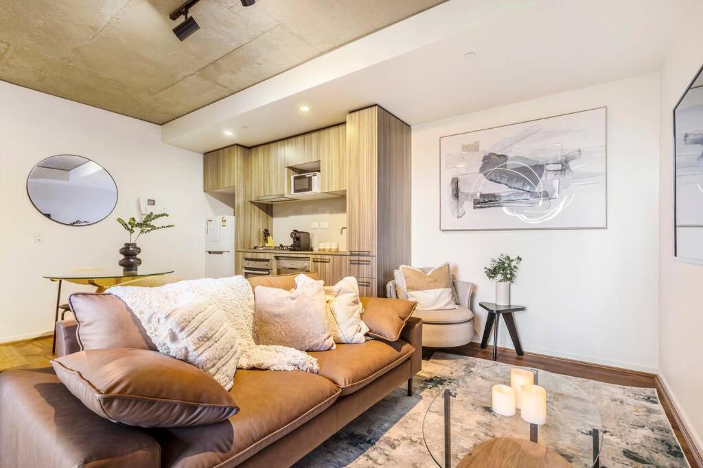 ein Wohnzimmer mit einem braunen Sofa und einer Küche in der Unterkunft Urban Hideaway in Melbourne's Epicentre in Melbourne