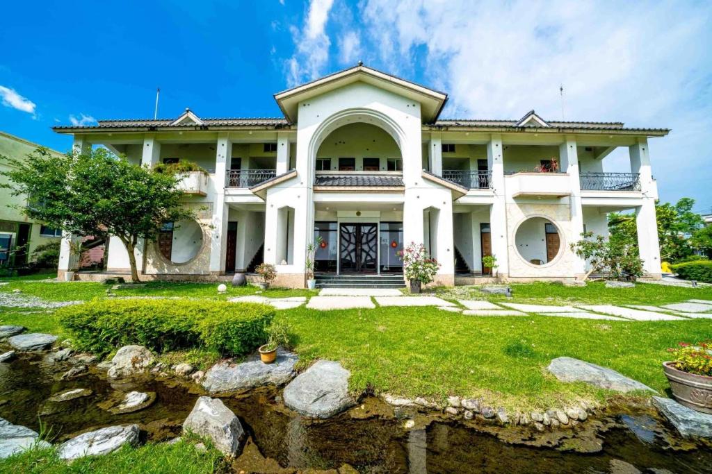 a large white house with a yard at Yun Tien Feng Chuan B&amp;B in Dongshan