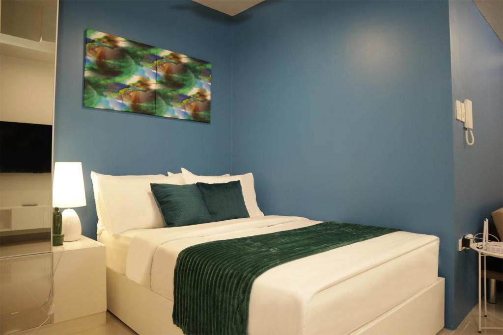 a bedroom with a white bed with a blue wall at Homefort at S Residences in Manila
