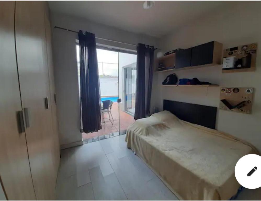ein Schlafzimmer mit einem Bett und einem großen Fenster in der Unterkunft Casaclassea in Juiz de Fora