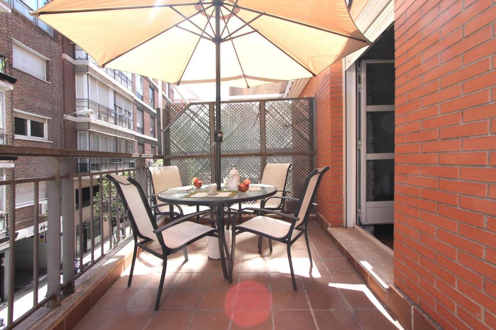 a table and chairs on a balcony with an umbrella at Apartamento Silvela in Madrid