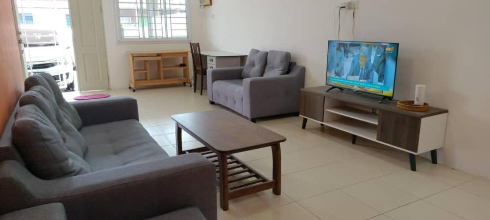 a living room with two couches and a flat screen tv at Moyan Square By Natol Homestay in Kuching