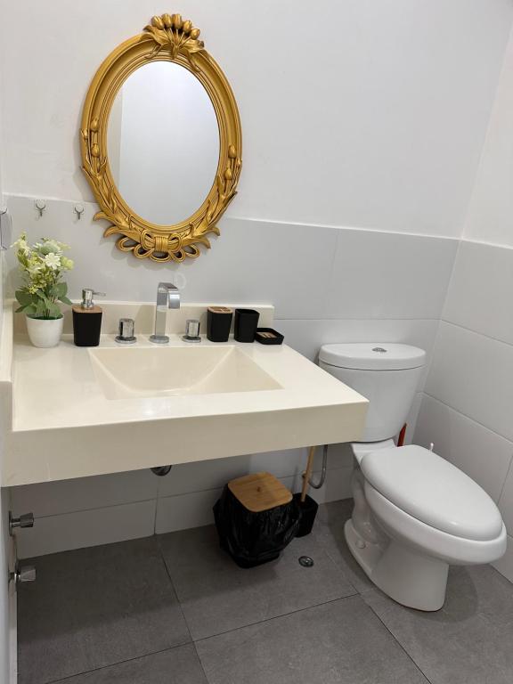 een badkamer met een wastafel, een toilet en een spiegel bij Hermoso Departamento a media Cuadra de la Av Javier Prado in Lima