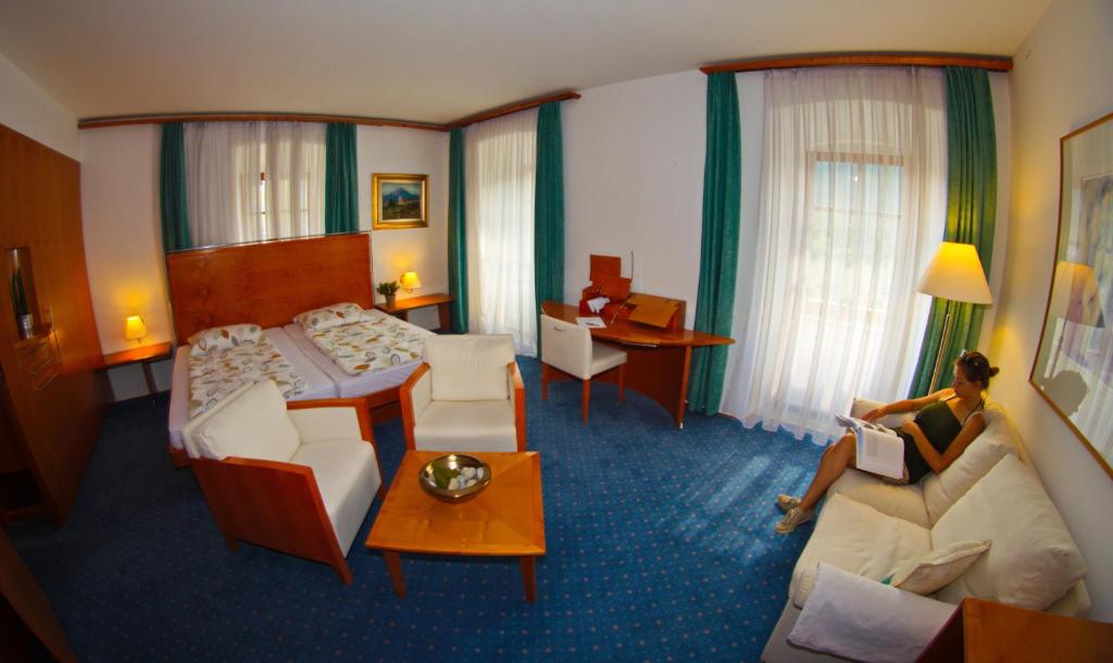 Rooms Savinja في لاشكو: امرأة جالسة على سرير في غرفة فندق