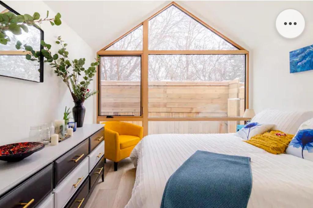 ein Schlafzimmer mit einem Bett, einem Fenster und einem gelben Stuhl in der Unterkunft Tiny House Haven in Peterborough