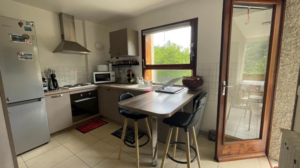 a kitchen with a table and two bar stools at Edelweiss de Vallouise-Pelvoux, 52m2 in Pelvoux