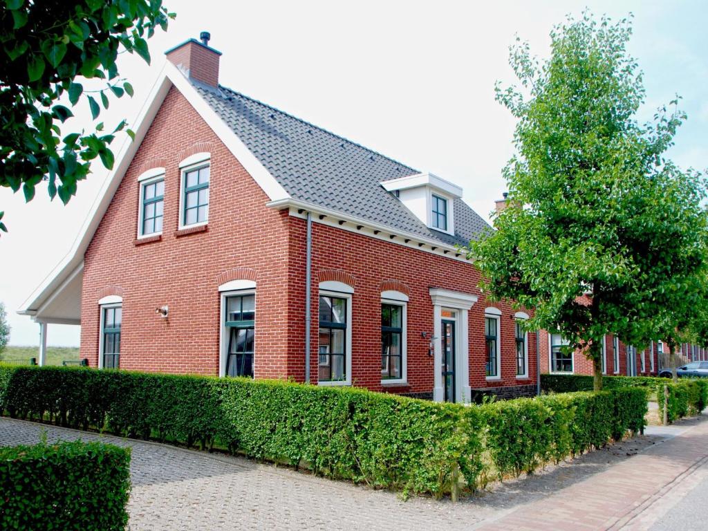 uma casa de tijolos vermelhos com uma árvore em frente em Vacation home with sauna in Zeeland em Colijnsplaat