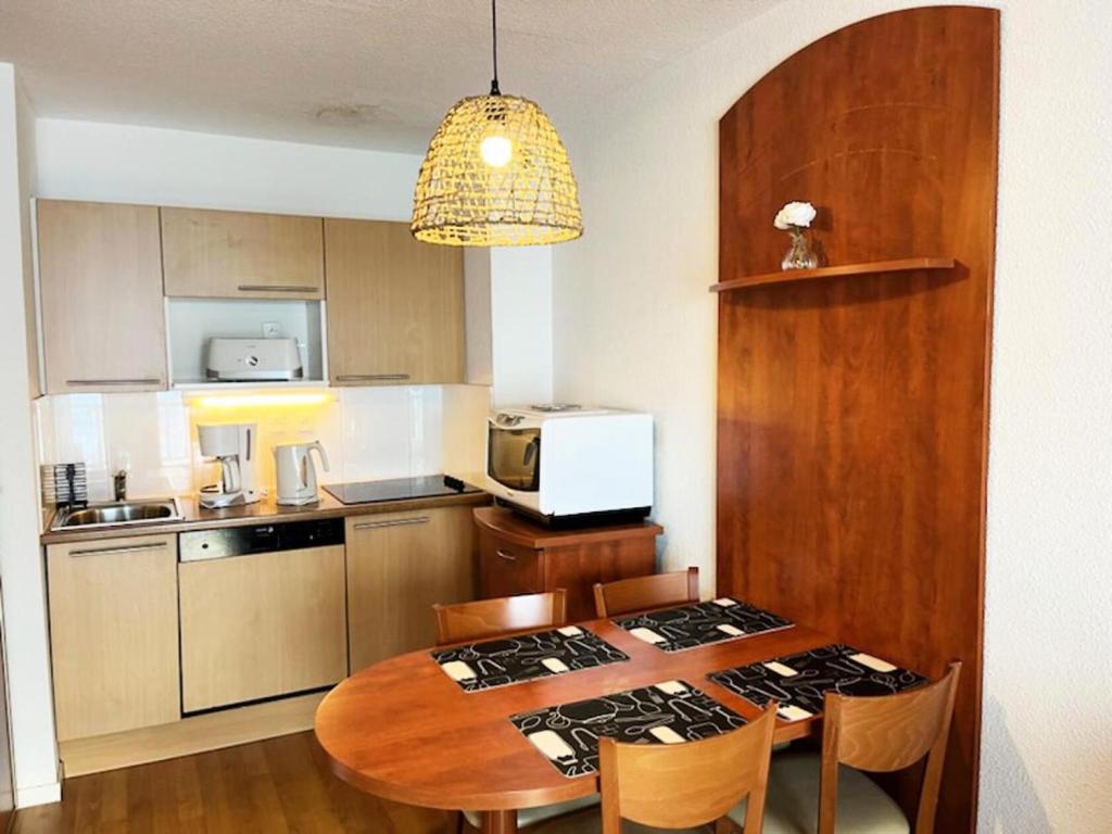 Il dispose d'une cuisine avec une table en bois et une cuisinière. dans l'établissement Résidence Pic Du Midi - Apt n°136 - Rez de chaussée - Bâtiment Hourquette MAE-8584, à La Mongie
