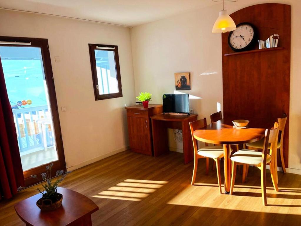 een woonkamer met een tafel en een klok aan de muur bij Résidence Pic Du Midi - Studio pour 4 Personnes 724 in La Mongie