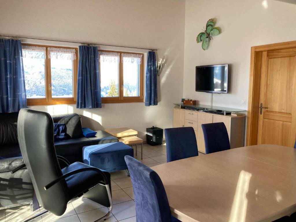 een woonkamer met een tafel en blauwe stoelen bij Chalet Lalula in Rosswald