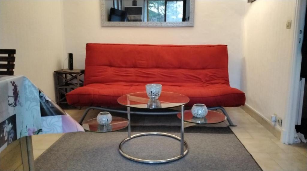 - un salon avec un canapé rouge et 2 tables dans l'établissement LA PETITE TOURELLE, à Thorenc