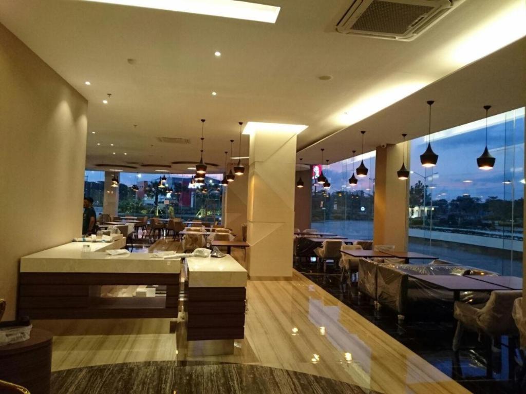 a restaurant with tables and chairs and a view of the city at Wing Hotel Kualanamu Airport in Kampungbesar