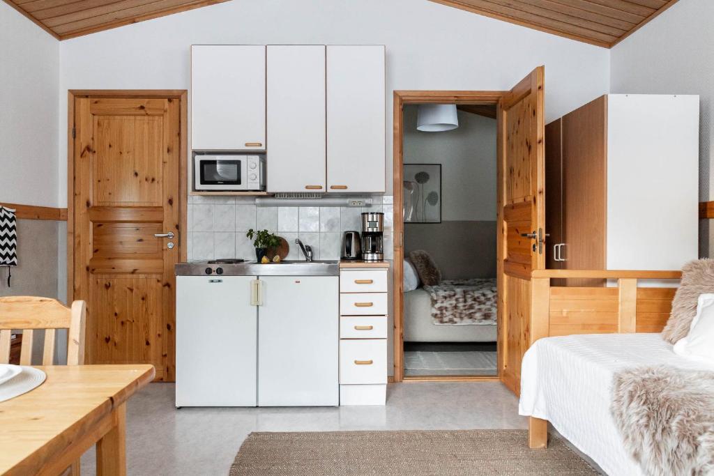 a kitchen with white cabinets and a bed in a room at Lapland Arctic Cabins 