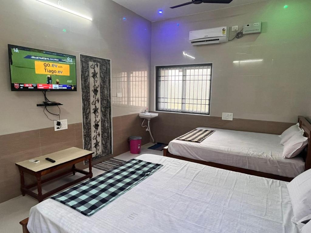 a room with two beds and a flat screen tv at MOHAN COTTAGE in Wodapatti