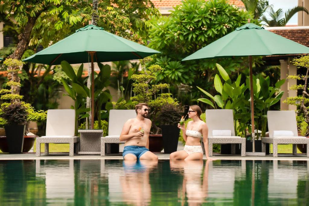 a man and a woman sitting in a swimming pool at HOI AN HISTORIC HOTEL in Hoi An