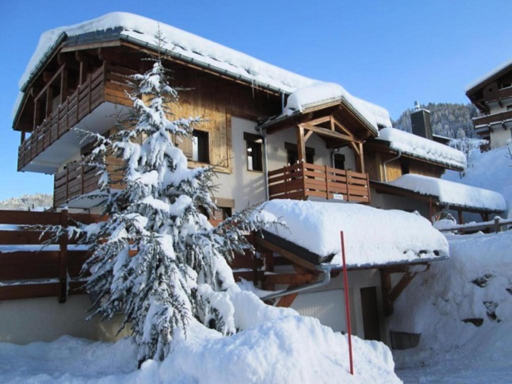 a snow covered tree in front of a house at Les Chalets Des Evettes - 3 Pièces pour 6 Personnes 64 in Notre-Dame-de-Bellecombe