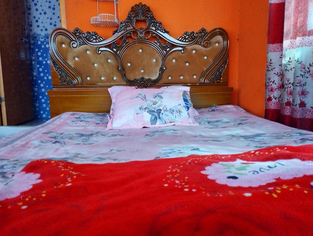 uma cama com uma cabeceira ornamentada e um cobertor vermelho em Hotel Short Time Stay em Dhaka