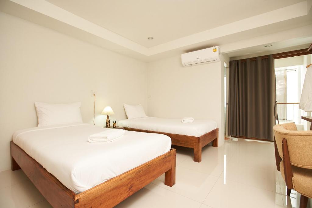 a hotel room with two beds and a chair at Imm Paknham in Ban Hin Sam Kon