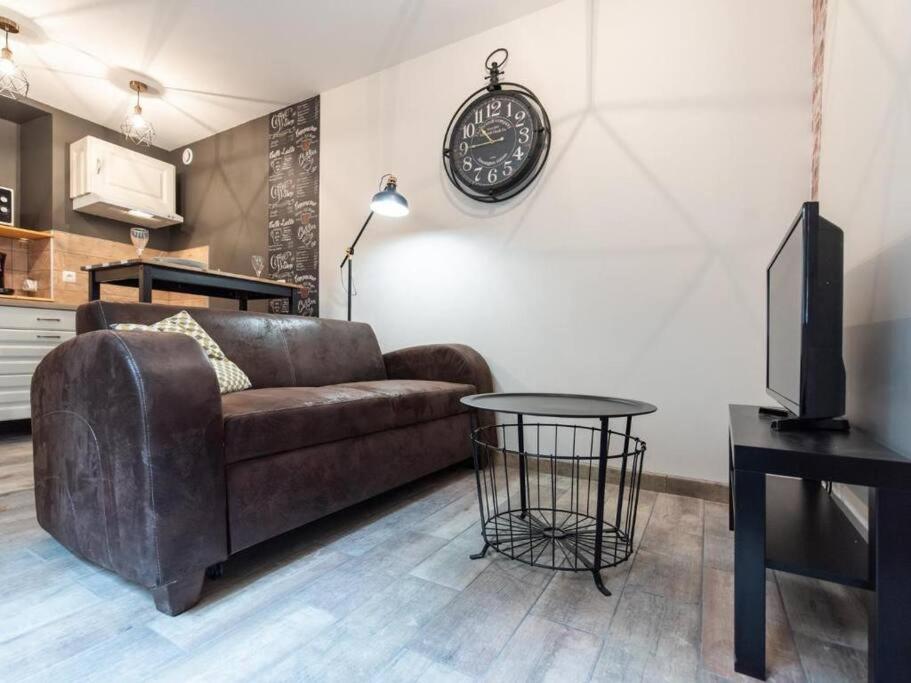 sala de estar con sofá y reloj en la pared en L'Atelier- appartement cosy avec cour - centre, en Bourgoin