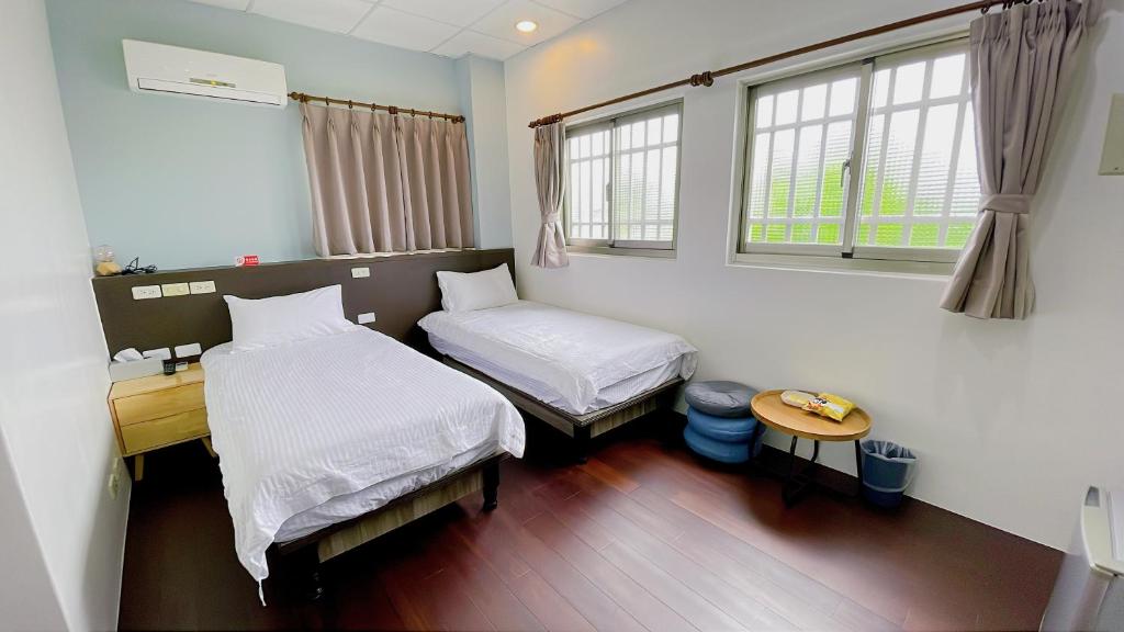 a room with two beds and a desk and two windows at Sun B&B in Taitung City