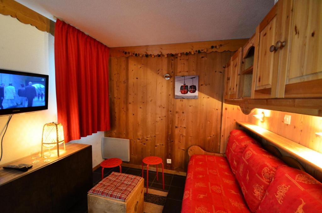 salon z czerwoną kanapą i telewizorem w obiekcie Résidence Villaret - Studio pour 4 Personnes 234 w Les Menuires