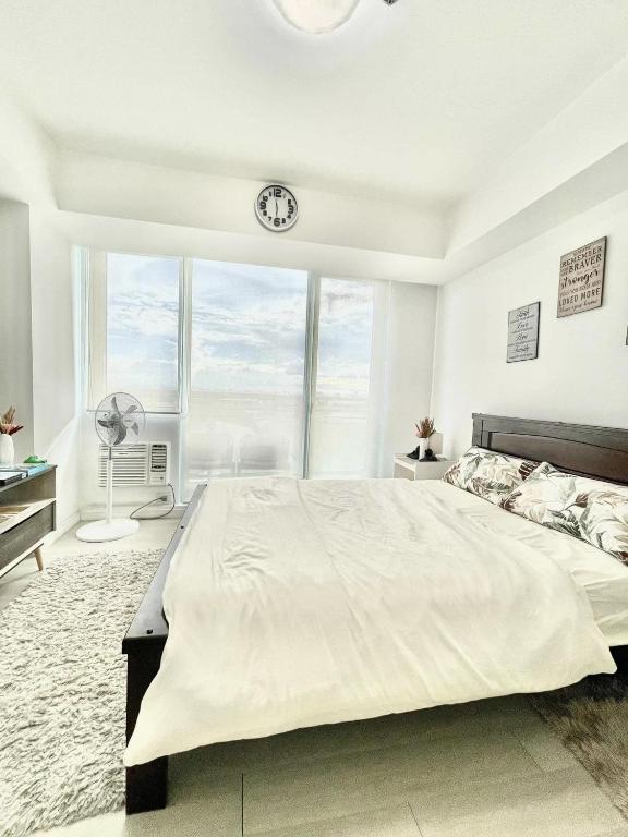 een slaapkamer met een groot bed en een klok aan de muur bij A3J Staycation at Azure Urban Resort Residences in Manilla
