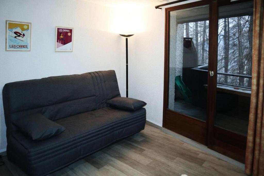 a living room with a couch and a glass door at Résidence LE PERESCUELLE - Studio pour 4 Personnes 624 in Les Orres