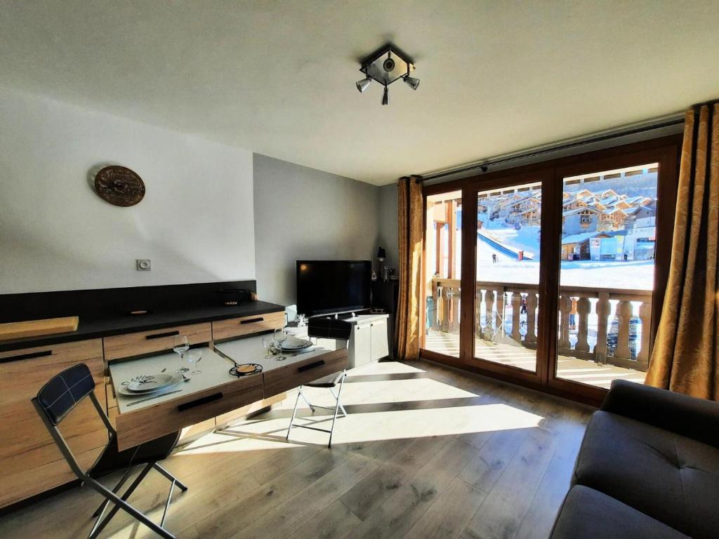ein Wohnzimmer mit einem TV und einem großen Fenster in der Unterkunft Résidence Dahlia - 2 Pièces pour 4 Personnes 304 in Saint-Martin-de-Belleville