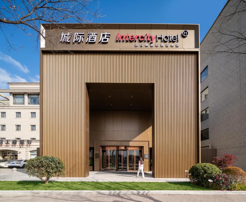 a woman walks into the entrance to an office building at IntercityHotel Shanghai Hongqiao Airport - Free Minibar for First Night in Shanghai