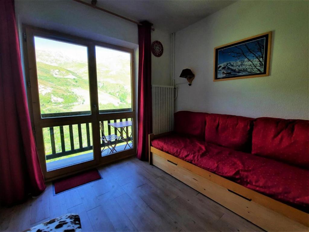 a living room with a red couch and a large window at Résidence Jetay - 2 Pièces pour 4 Personnes 614 in Les Menuires