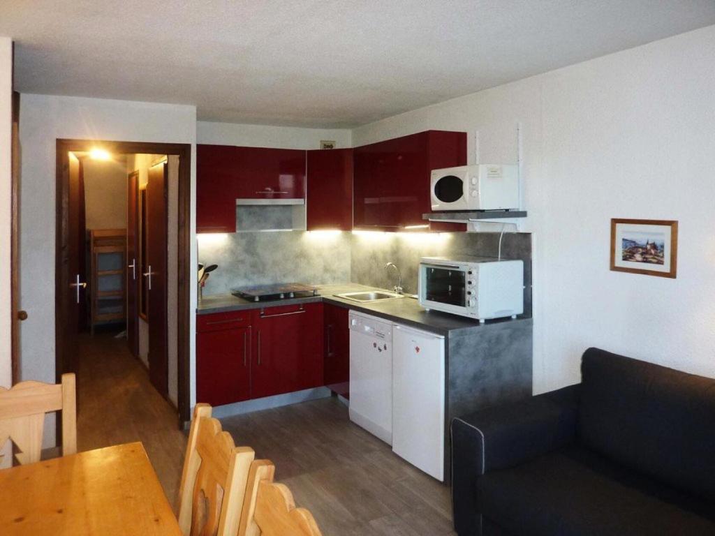 une petite cuisine avec des placards rouges et un four micro-ondes dans l'établissement Résidence Le Cairn - Studio 4/6 personnes MAE-7344, aux Orres