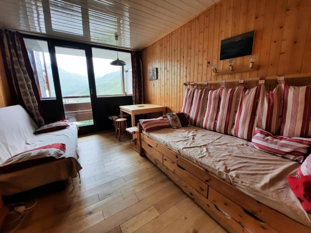 een slaapkamer met een bank in een kamer met houten wanden bij Résidence Alpages - Studio pour 3 Personnes 904 in Les Menuires
