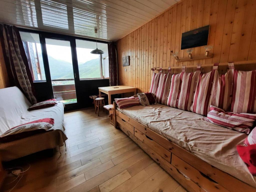 - une chambre avec un canapé dans une pièce dotée de murs en bois dans l'établissement Résidence Alpages - Appartement pour 2 personnes avec balcon exposé Sud MAE-5904, aux Menuires