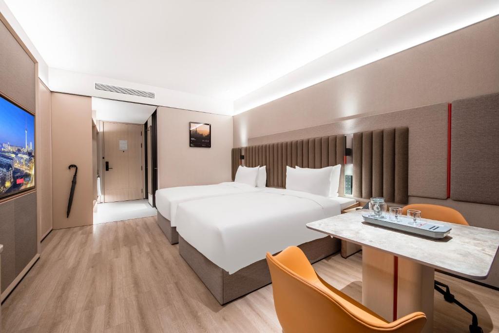 a hotel room with a large bed and a desk at IntercityHotel Shanghai Hongqiao Airport - Free Minibar for First Night in Shanghai