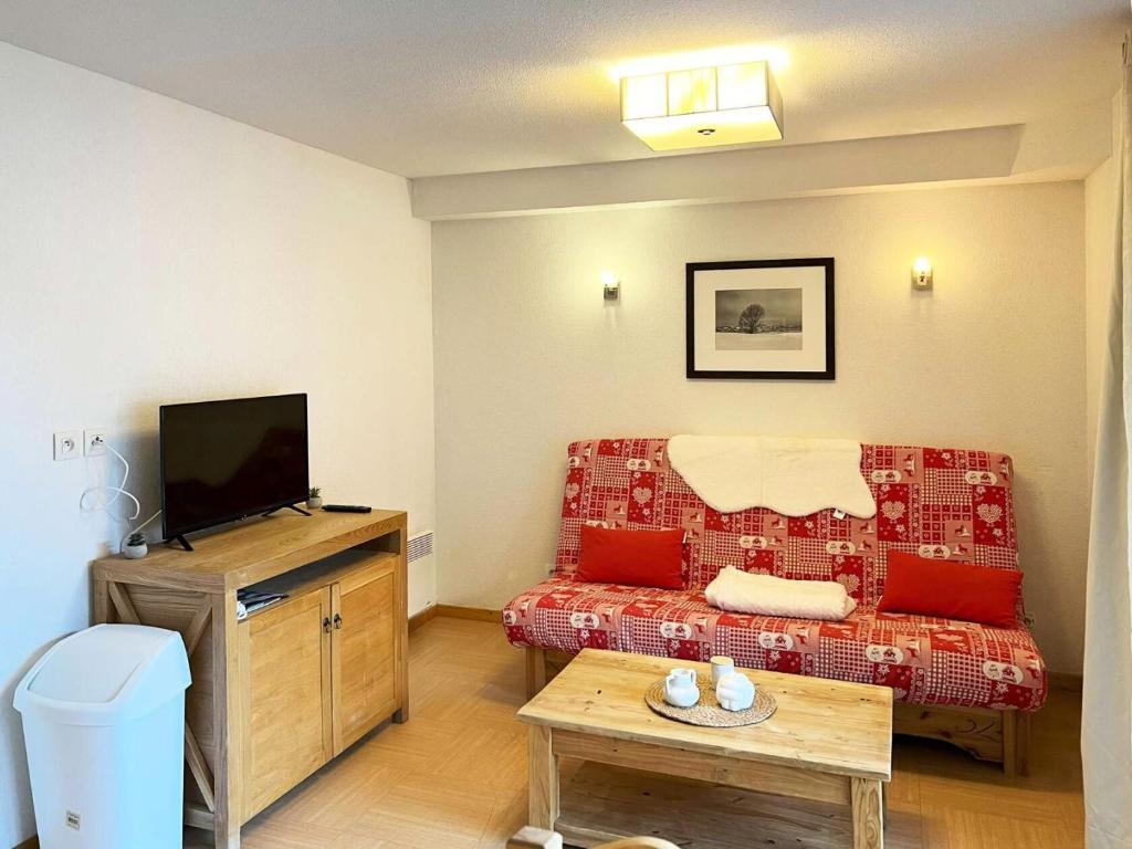 a living room with a red couch and a flat screen tv at Résidence Parc Des Airelles - Studio pour 4 Personnes 734 in Le Mélézet