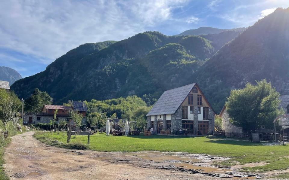 una casa su un campo con montagne sullo sfondo di Petriti theth a Theth