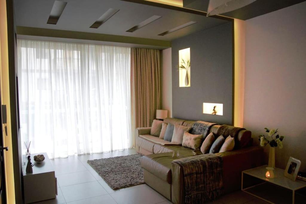 a living room with a couch and a large window at Modern 3BR Apartment in Swieqi in Is-Swieqi