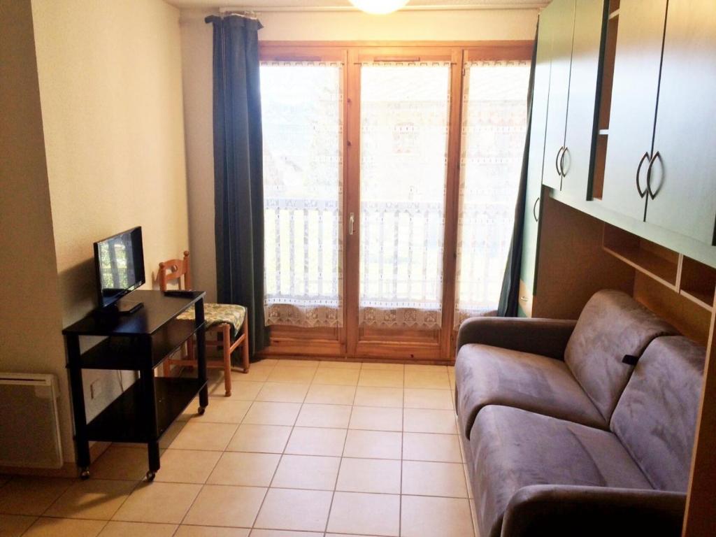 a living room with a couch and a desk and a window at Résidence Plane - Studio pour 4 Personnes 574 in Montgenèvre