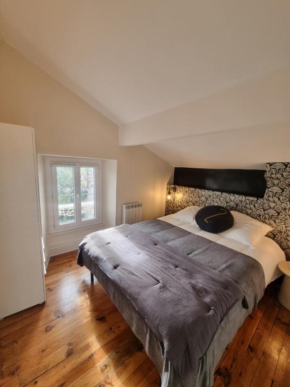 a bedroom with a large bed with a wooden floor at Villa St-Gau in Saint-Gaudens