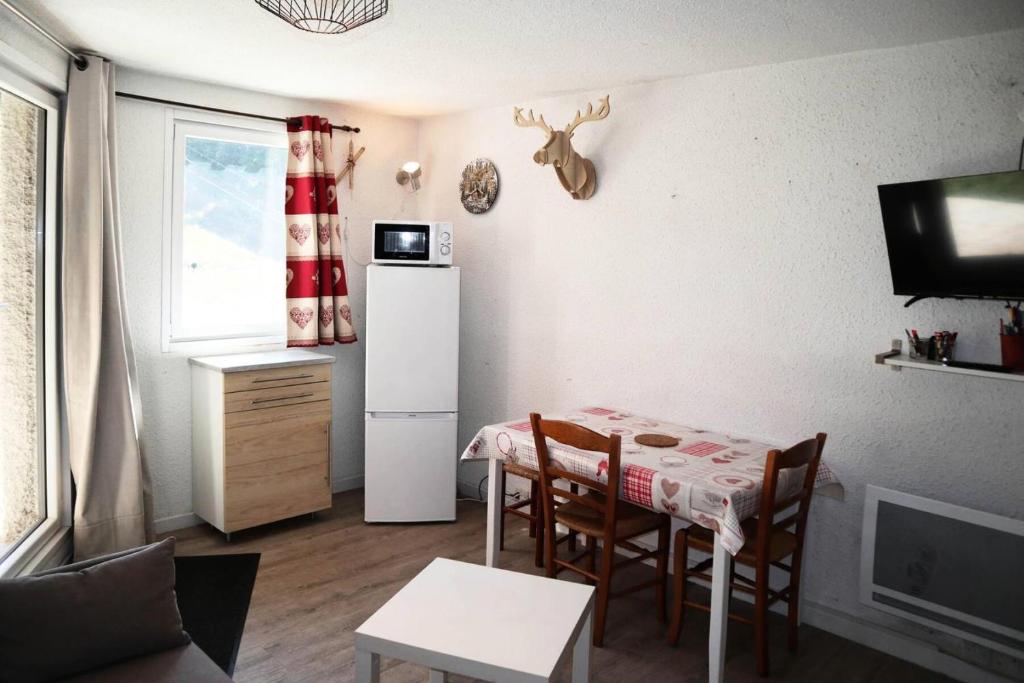 una piccola cucina con tavolo e frigorifero bianco di Résidence Pic Vert - Studio pour 4 Personnes 204 a Les Orres