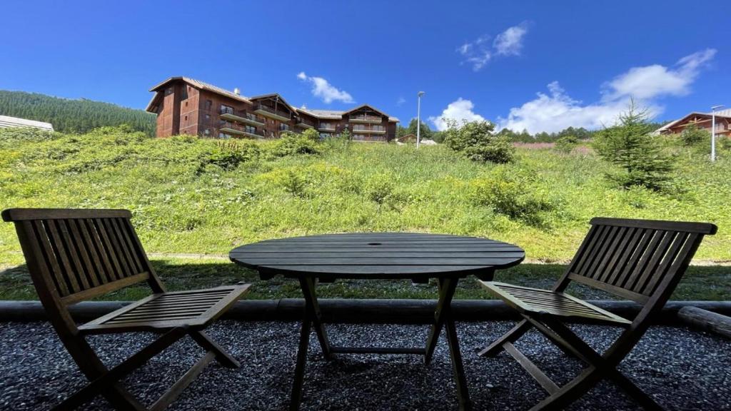 une table en bois et deux chaises assises à côté d'une table dans l'établissement Résidence Dame Blanche - DBA119 - APPT 1 CHAMBRE + CABINE - BALCON - 6 PERSONNES MAE-7994, à Narreyroux