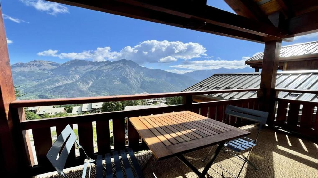 una mesa de madera en un balcón con vistas a las montañas en Résidence Dame Blanche - 2 Pièces pour 6 Personnes 954, en Narreyroux