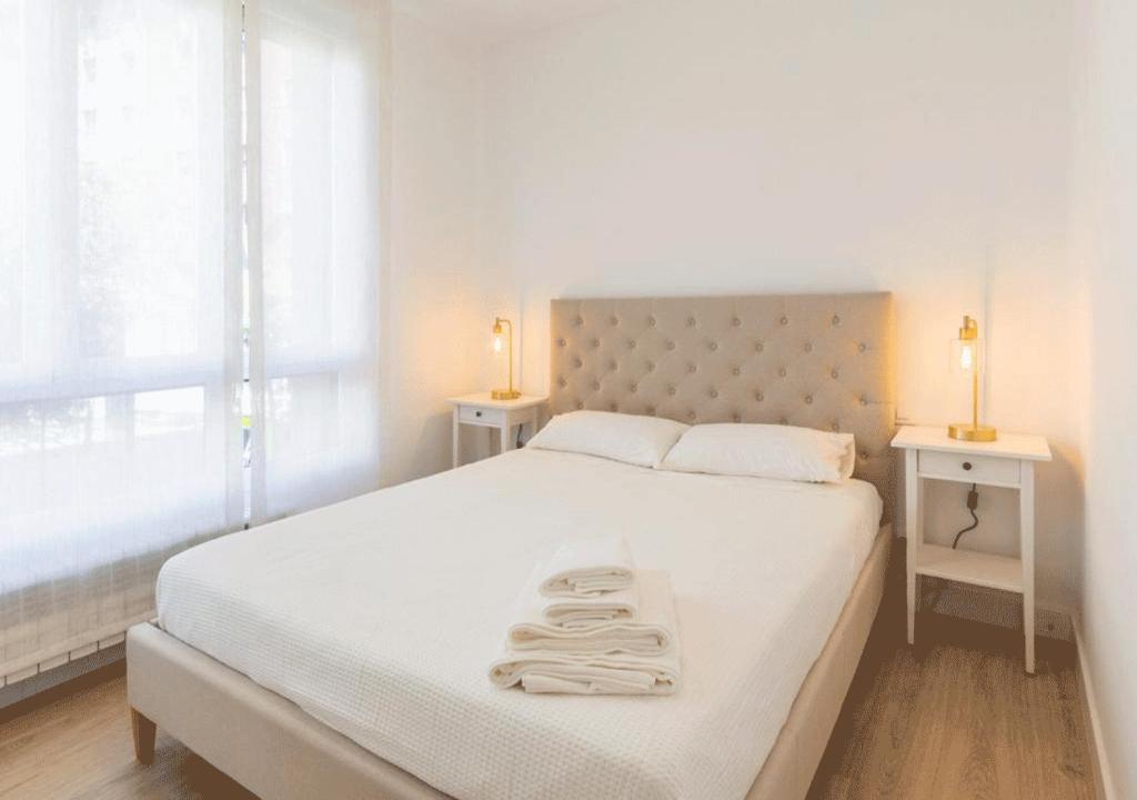 een witte slaapkamer met een groot bed met 2 nachtkastjes bij Apartamento en Colón - Logroño in Logroño